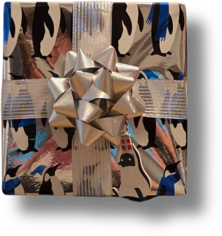 A parcel in penguin paper with silver ribbon, a silver bow and a little penguin tag